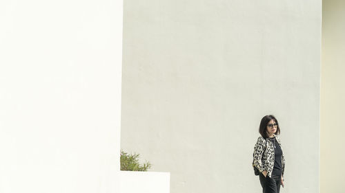 Portrait of woman standing against wall