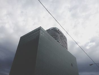 Low angle view of modern building against cloudy sky