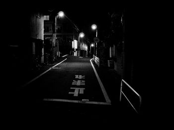 Empty road along buildings at night