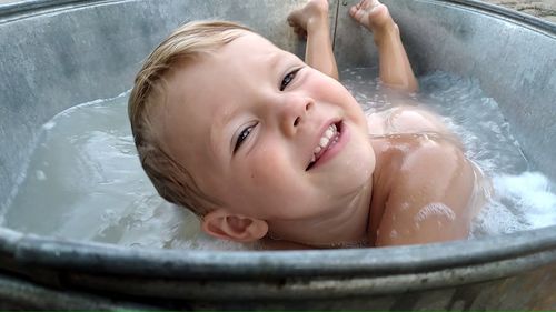 Smiling boy in the bathtub with foam