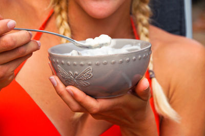 Midsection of young woman holding food in bowl