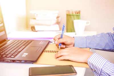 Midsection of woman using laptop on table