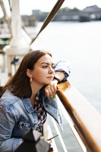 Young woman looking away while sitting on boat in sea