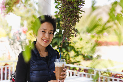 Happy woman hand holding iced coffee latte in cafe outdoor.