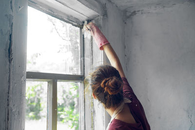 Rear view of woman by window at home