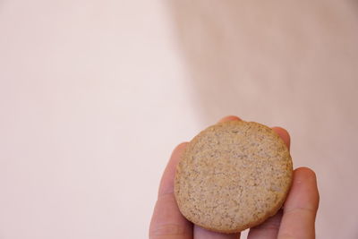 Close-up of hand holding bread against white background