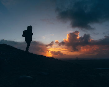 Silhouette man standing on land against sky during sunset