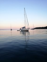 Sailboats sailing in sea against clear sky