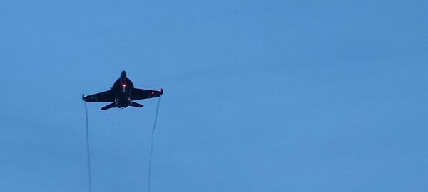 Low angle view of airplane flying against clear blue sky