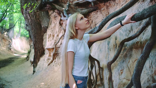 Full length of woman standing by tree trunk