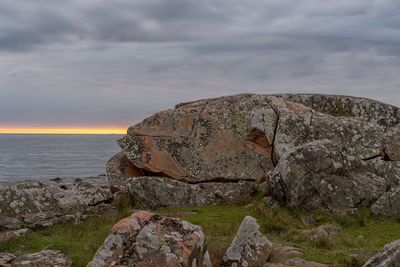 Rock formation on beach against sky during sunset