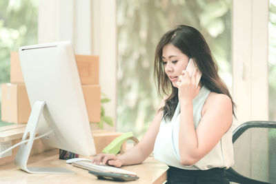 Young woman using phone while sitting on table