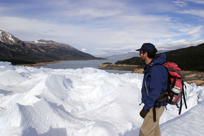 Man standing on snowcapped mountain against sky