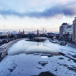 Bridge over river amidst buildings in city against sky