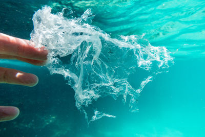 Cropped hand of man swimming in sea