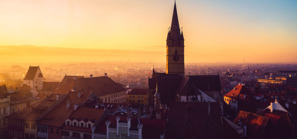 Aerial view of buildings in city at sunset