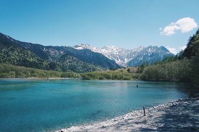 Scenic view of lake and mountains against blue sky