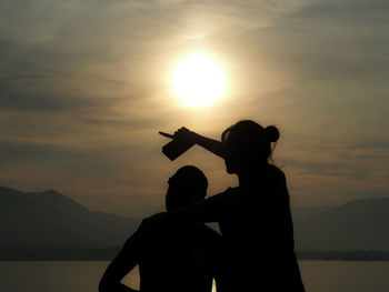 Silhouette people on mountain against sky during sunset