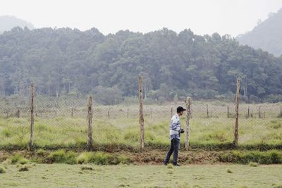 Full length of boy standing on field against sky