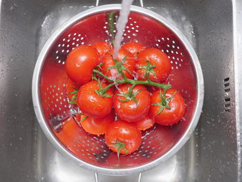 High angle view of water falling on tomatoes in colander