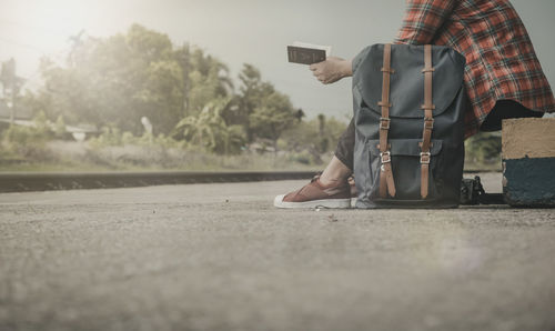 Low section of man with passport sitting on footpath