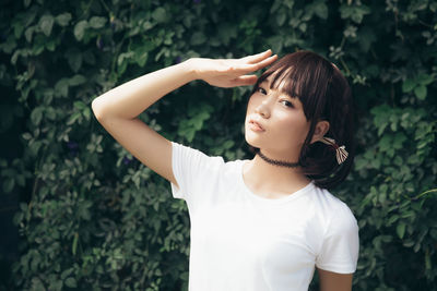 Girl looking away while standing against plants