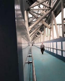 Rear view of man walking on bridge