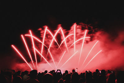 Crowd looking at firework display during night