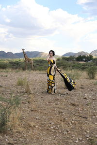 Woman in dress standing on field against sky