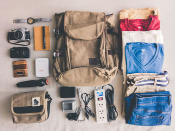 Directly above shot of cloths with bags and personal accessory on table