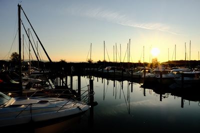 Sailboats moored at harbor during sunset