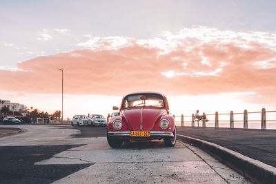 Cars on road against sky during sunset