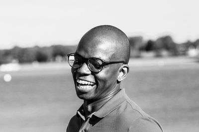 Close-up of young man laughing against sky