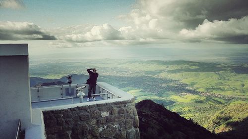 High angle view of man photographing at observation point against cloudy sky