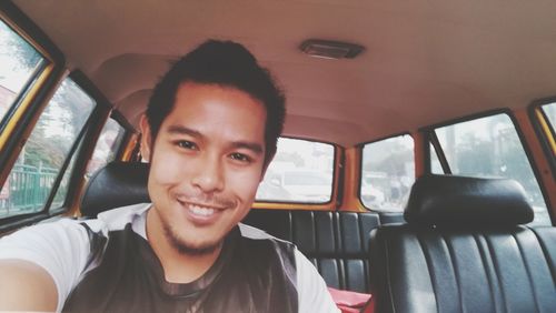 Portrait of smiling young man sitting in car