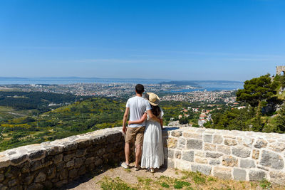 Rear view of young couple standing at klis fortress above city of split, croatia
