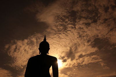 Low angle view of silhouette buddha statue against sky during sunset
