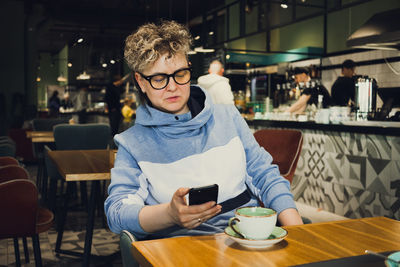 Mature woman using phone at cafe