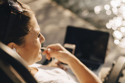 High angle close-up of woman talking through headphones during summer