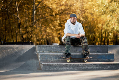 Full length of man with skateboard sitting on steps