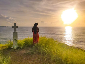 Woman looking at sea against sky during sunset