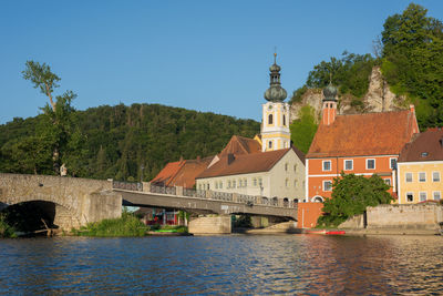 View of buildings by river against sky