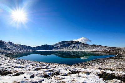 Scenic view of lake and mountains against clear blue sky