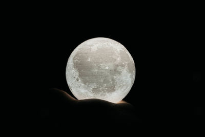 Close-up of hand holding moon over black background