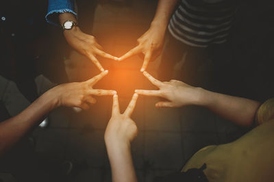 Close-up of people making star shape with hands
