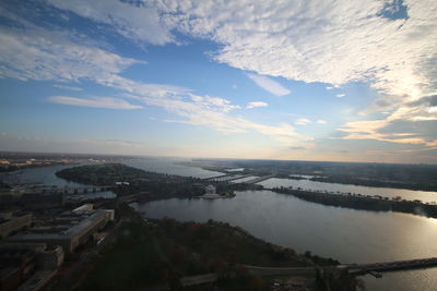 Aerial view of city by sea against sky
