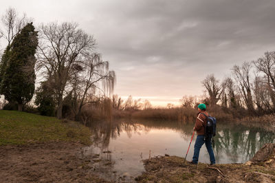 Man standing on bare tree against sky