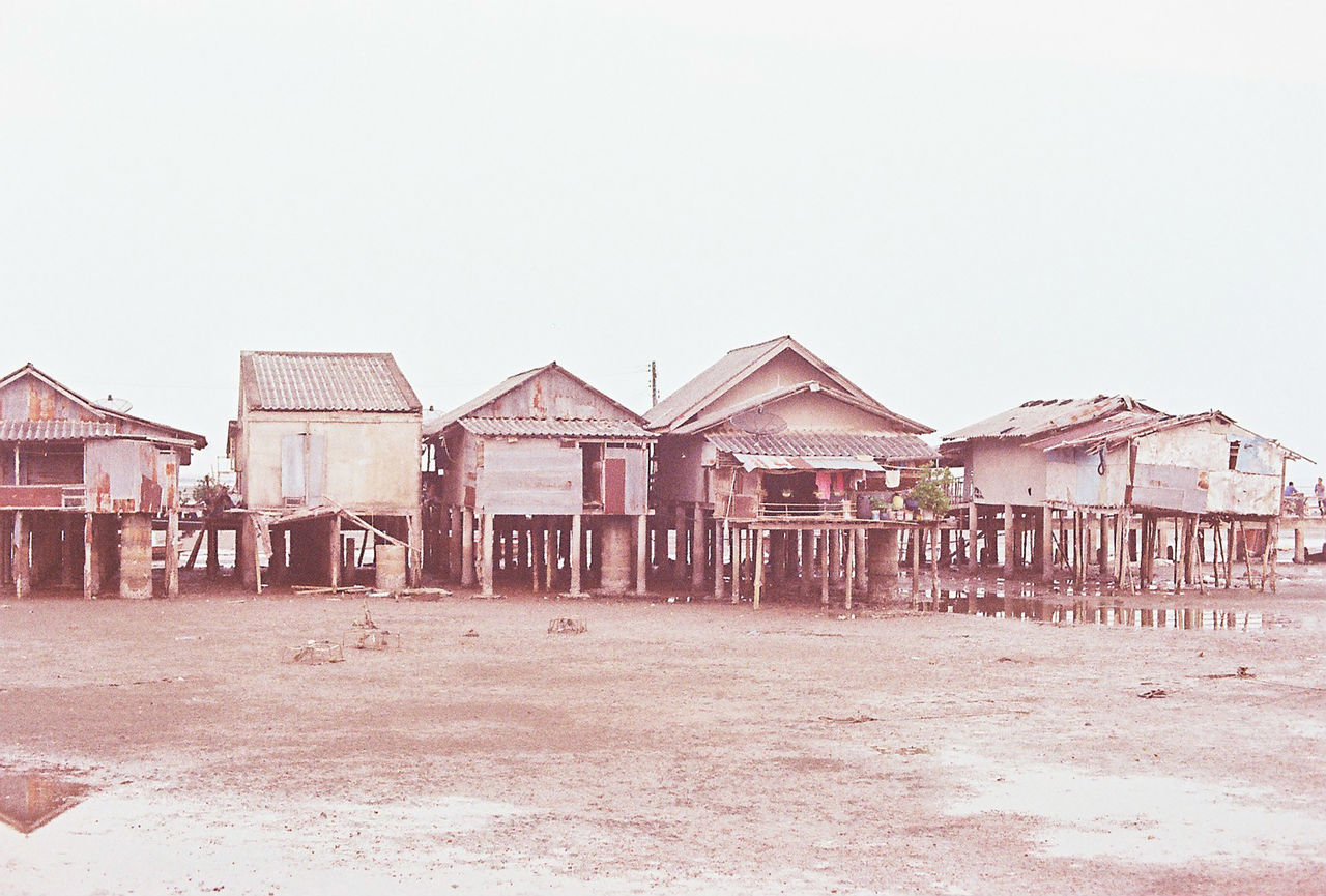 STILT HOUSES ON BEACH AGAINST SKY