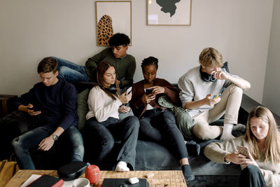 Teenage male and female friends using social media on smart phones at home