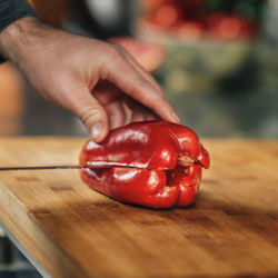 Cooking dinner - chef holding a knife and cutting red bell pepper